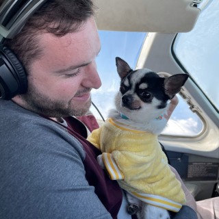 small white dog and man in airplane cockpit