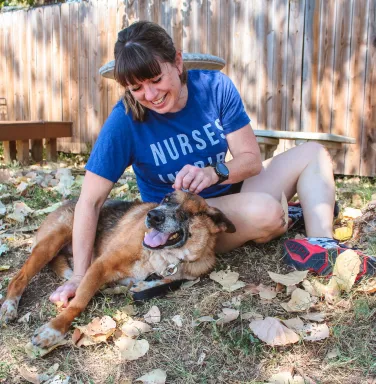 dog and woman playing in the grass