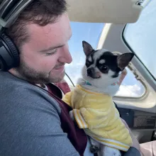 small white dog and man in airplane cockpit