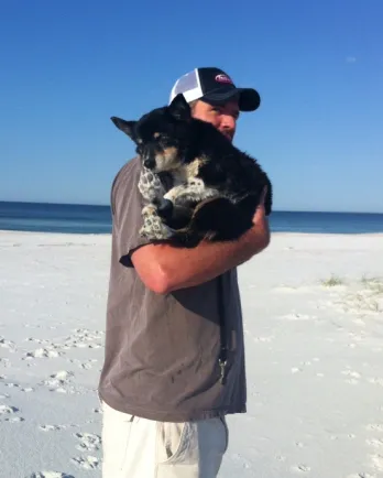 David walking on the beach with Hops curled in his arms