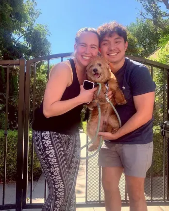 brown dog being held by 2 people