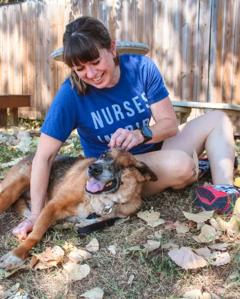 dog and woman playing in the grass