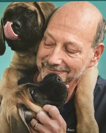 smiling man with 2 brown puppies